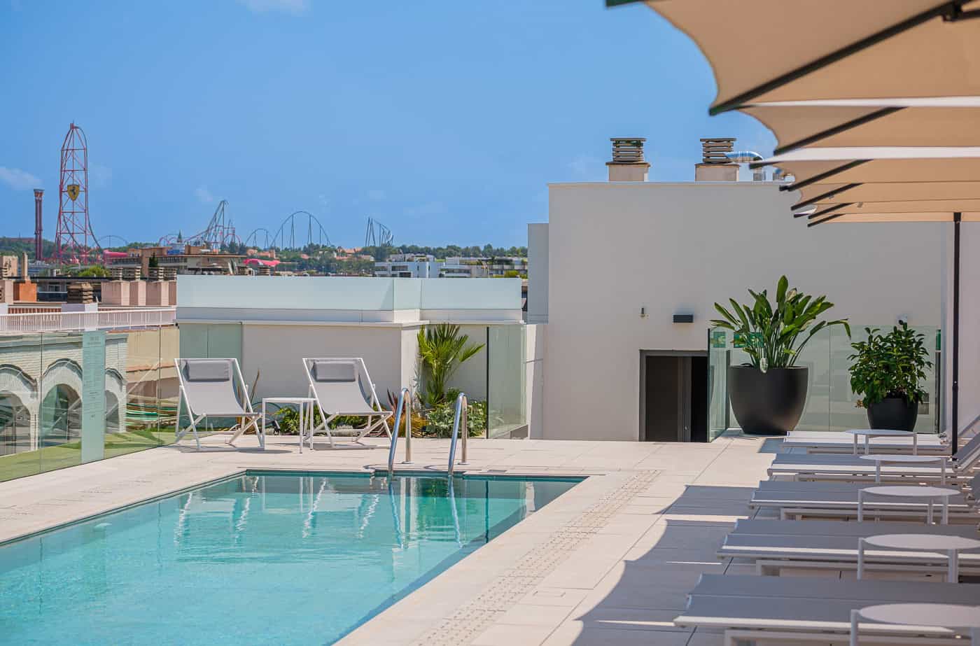 Piscina en azotea con vistas urbanas y sombrillas en terraza moderna.