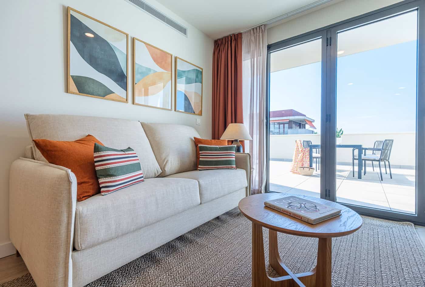 Sala de estar moderna con sofá y vista al balcón con terraza y mar.