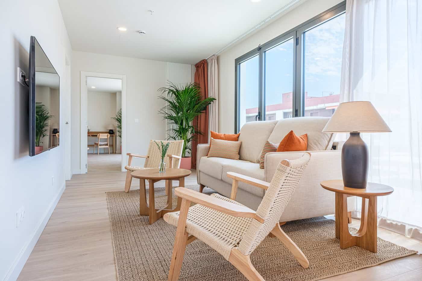 Sala de estar moderna con sofá, sillones y gran ventana con vista a la ciudad.